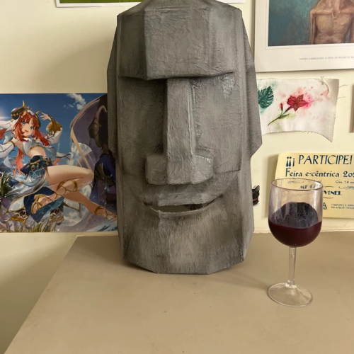 Homemade Moai mask next to a glass of wine on a table