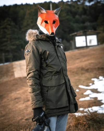 Photographer with geometric fox mask in forest